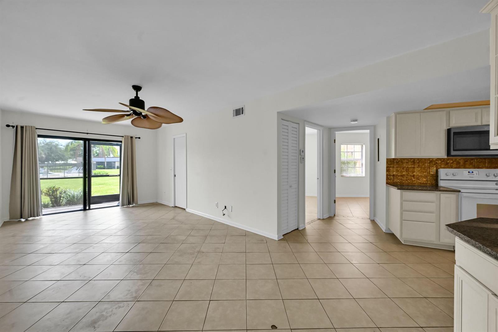 An open-concept living area with tile floors, a ceiling fan, and an adjacent kitchen — 2013 NE Collins Circle # 50, Jensen Beach FL 34957, JENSEN BEACH, FL