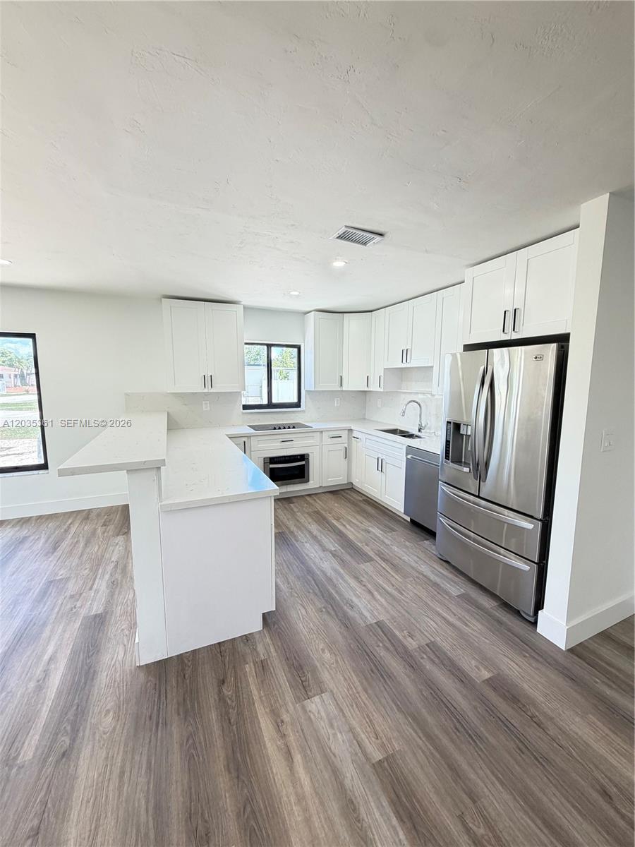 A modern kitchen features white cabinets, stainless steel appliances, and light-colored countertops — 2930 SW 106th Ave, Miami FL 33165, MIAMI, FL