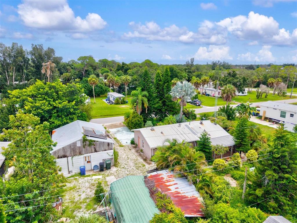 A detached garage with a roll-up door sits on a gravel lot with paved accents — 507 PINEWOOD AVENUE, NOKOMIS, FL