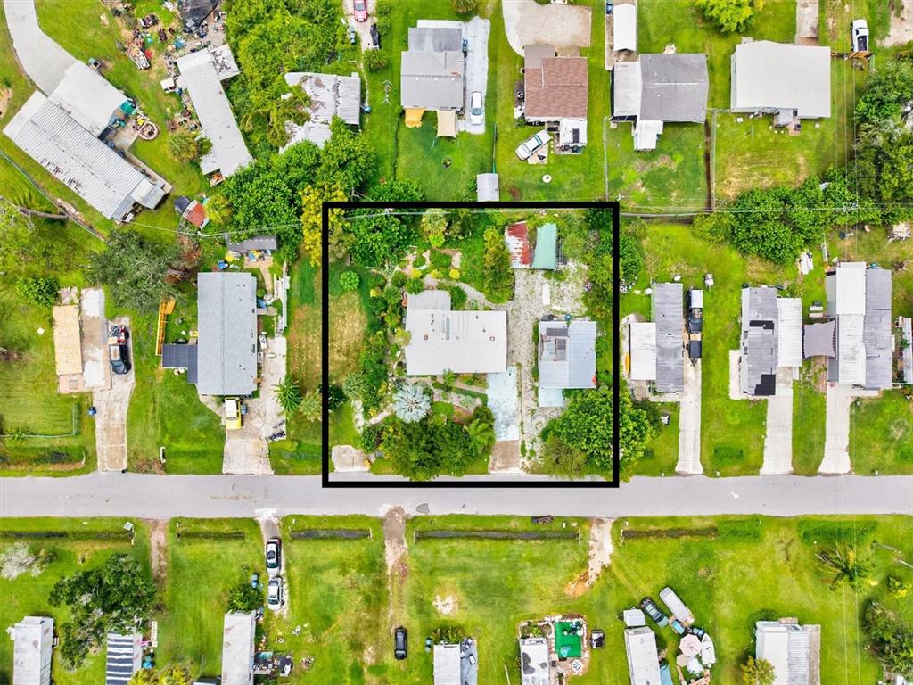 An aerial view shows two small houses with metal roofs surrounded by lush green trees — 507 PINEWOOD AVENUE, NOKOMIS, FL