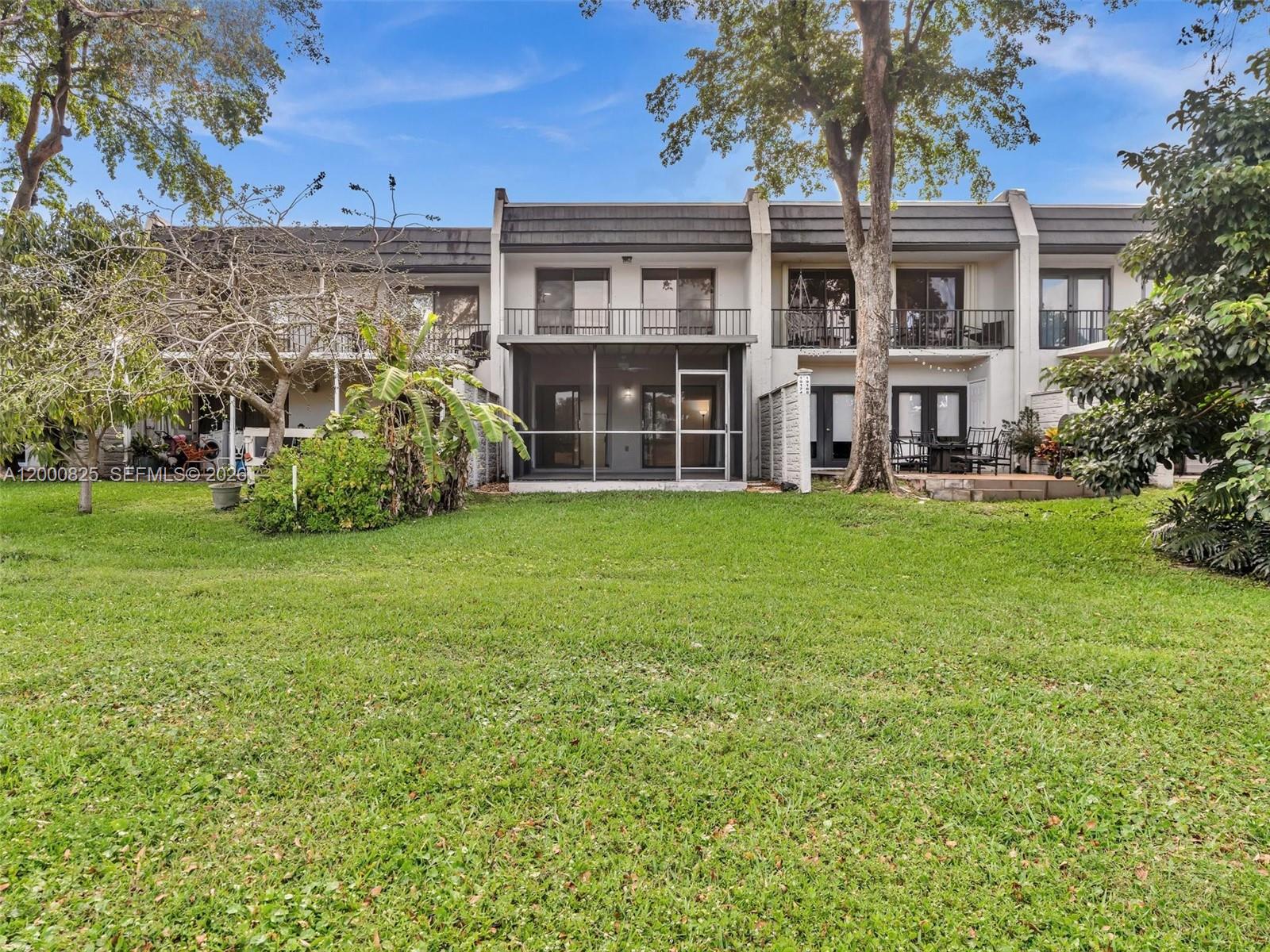 A multi-story townhouse complex features a shared backyard, screened-in patios, and second-floor balconies — 19174 Bobolink Dr, Hialeah FL 33015, HIALEAH, FL