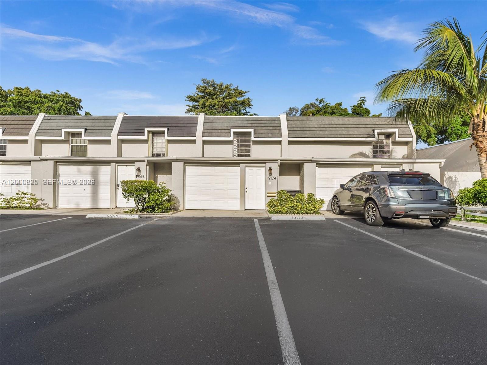 A row of townhouses with attached garages and a parked car in the foreground — 19174 Bobolink Dr, Hialeah FL 33015, HIALEAH, FL