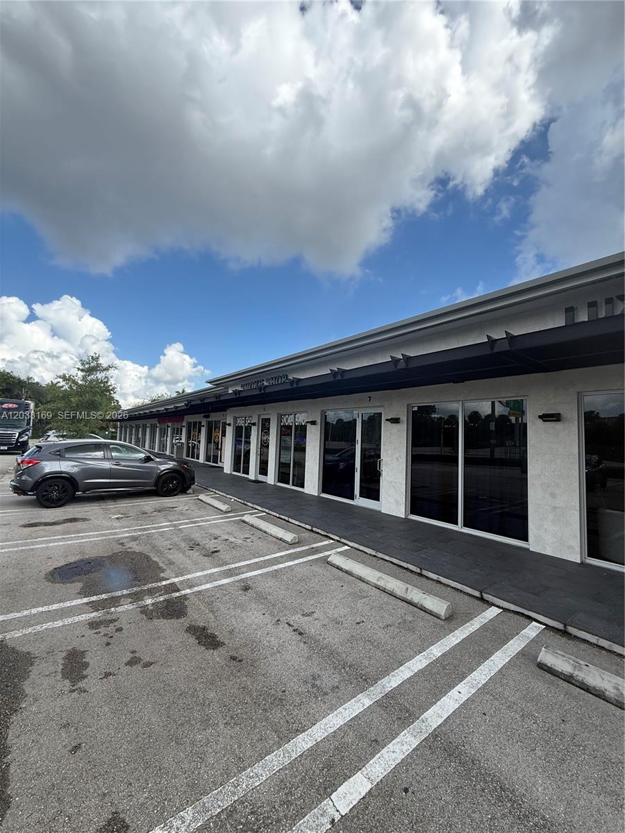 A gray SUV is parked in front of a commercial strip mall with glass storefronts — 8205 NW 12th St, Doral FL 33126, DORAL, FL