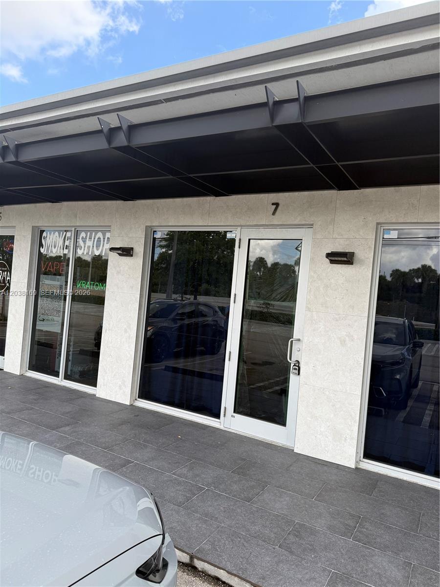 The exterior of a commercial storefront features a glass door, large windows, and stone cladding — 8205 NW 12th St, Doral FL 33126, DORAL, FL