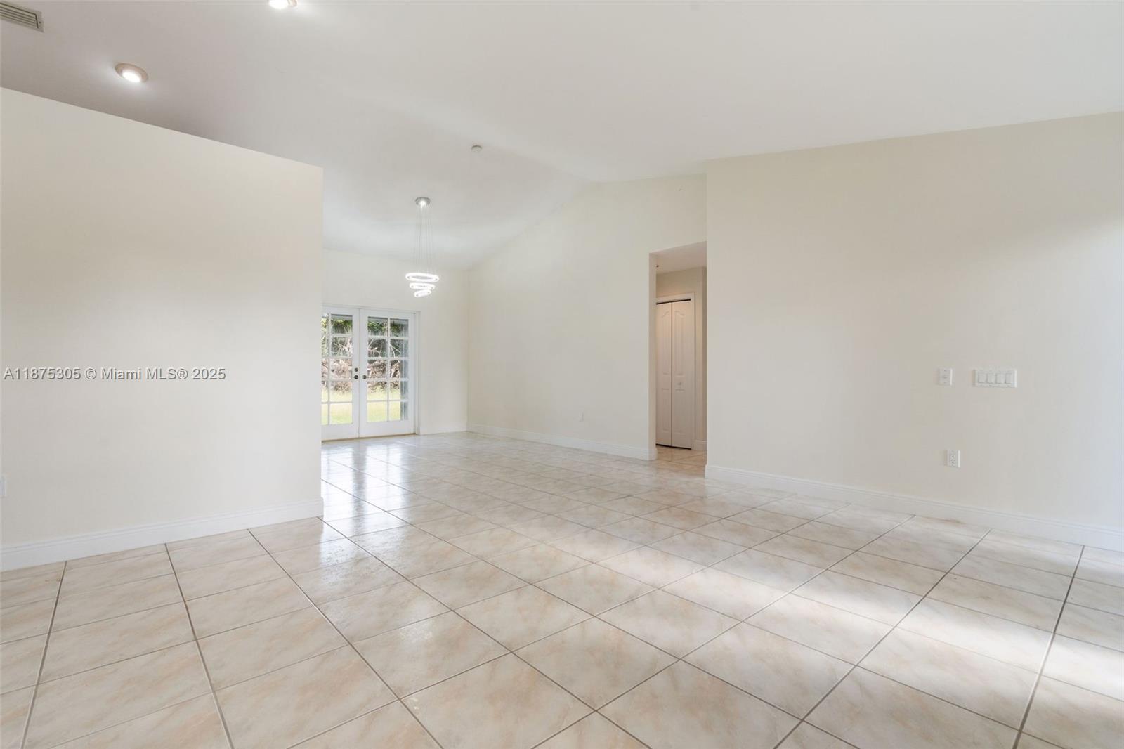 An empty room features light-colored tile flooring, white walls, recessed lighting, and glass French doors — 16035 SW 173rd Ave, Miami FL 33187, MIAMI, FL