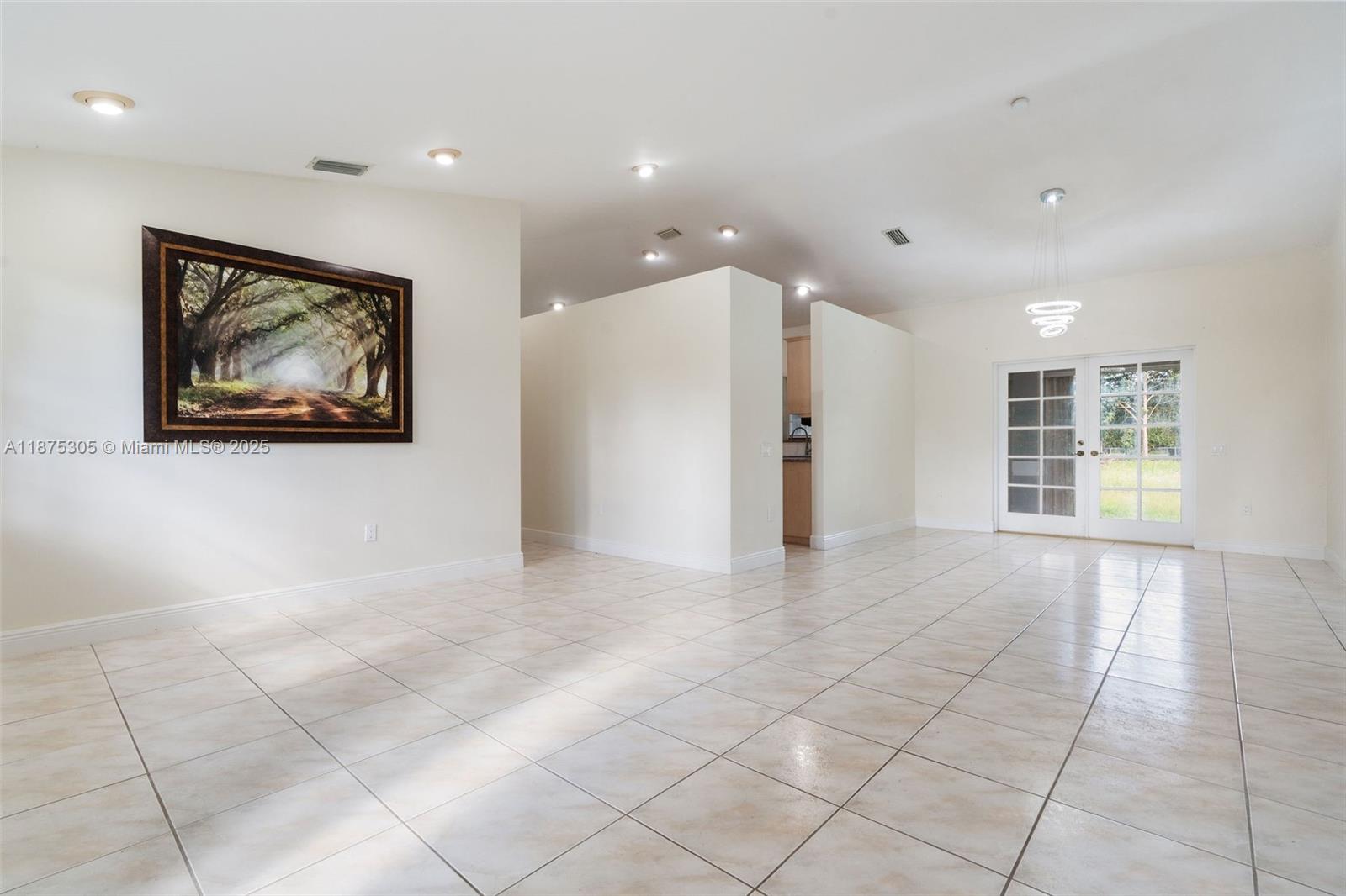 A spacious room features light-colored tile flooring, recessed lighting, and a large framed wall art — 16035 SW 173rd Ave, Miami FL 33187, MIAMI, FL