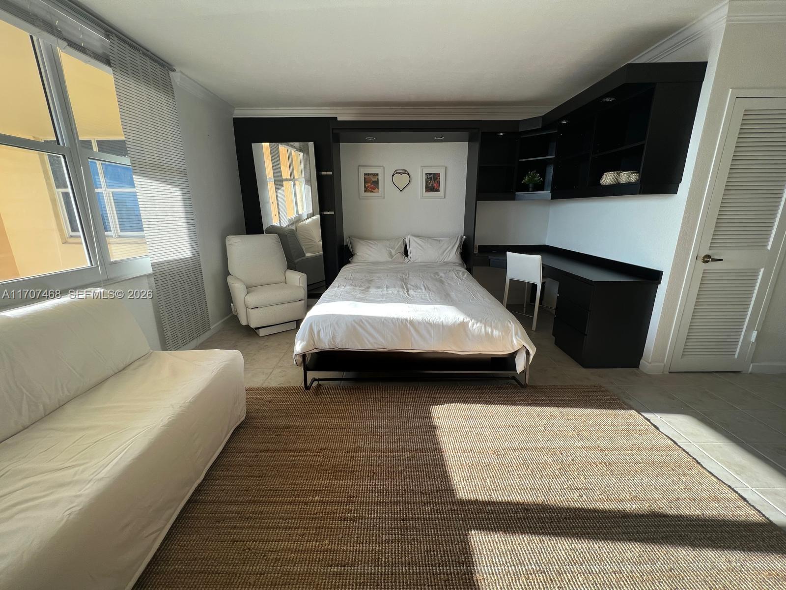 A bedroom features a Murphy bed, built-in desk, white armchair, and a large area rug — 2501 S Ocean Dr, Hollywood FL 33019, HOLLYWOOD, FL