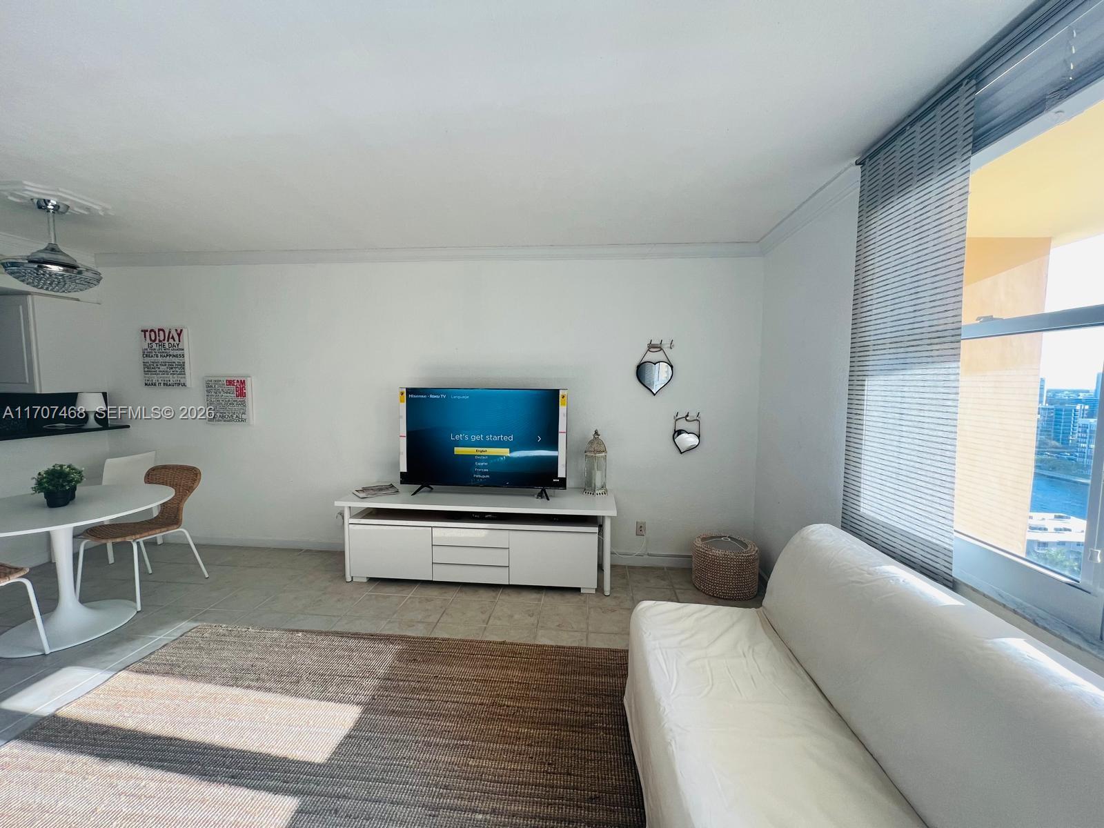 A living room features a white media console, a television, a sofa, and a dining area — 2501 S Ocean Dr, Hollywood FL 33019, HOLLYWOOD, FL
