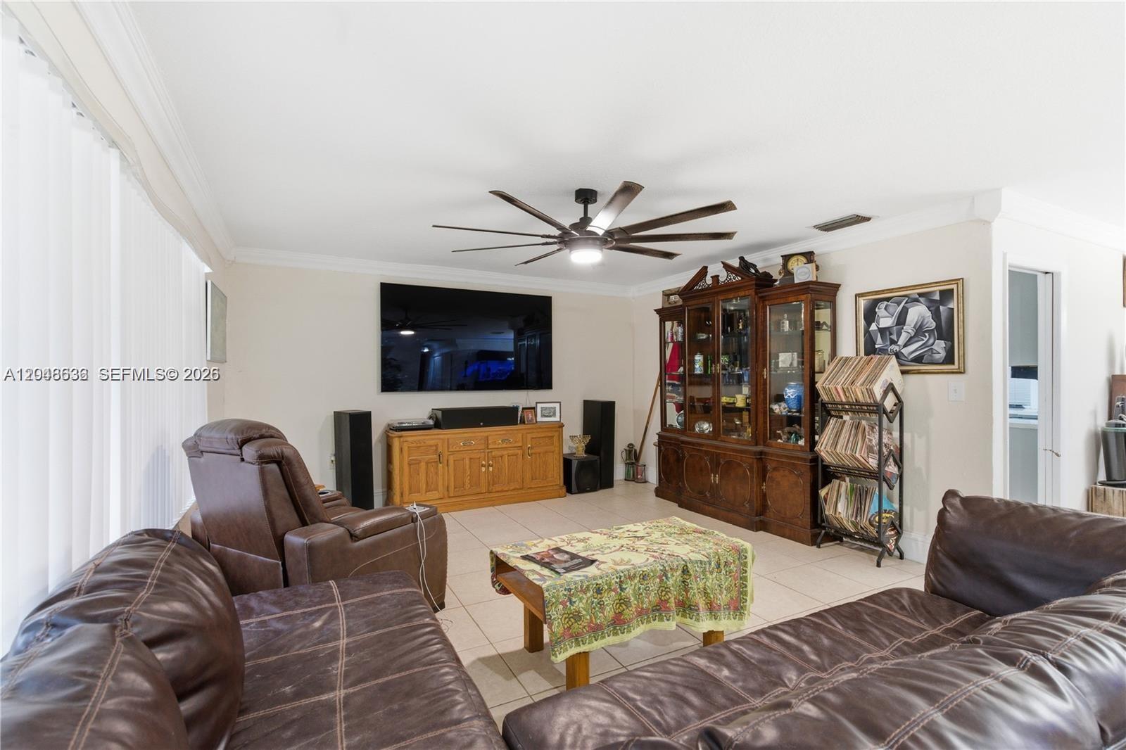 A living room features brown leather furniture, a large television, and a wooden display cabinet — 15490 SW 209th Ave, Miami FL 33187, MIAMI, FL