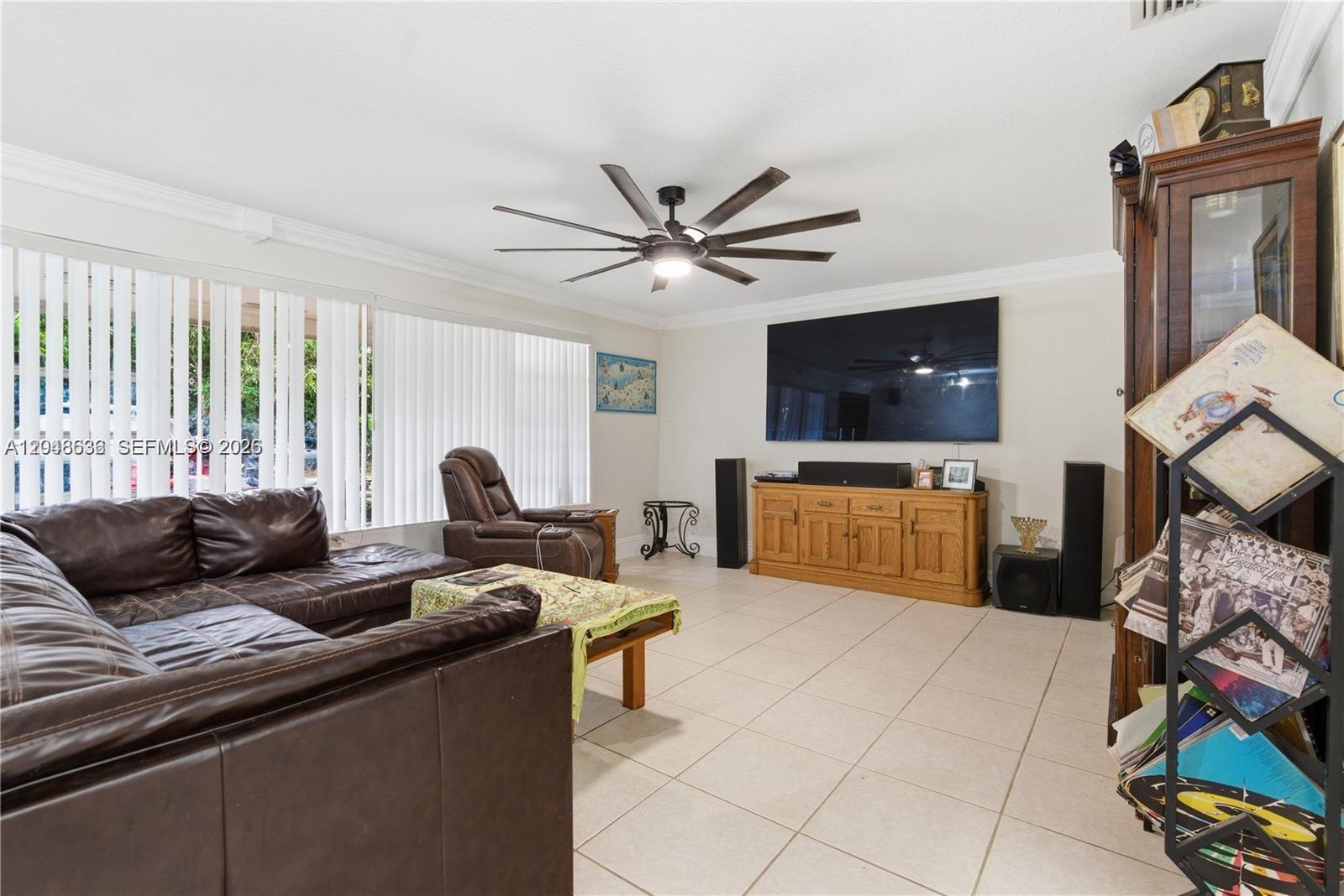 A living room features a large television, a leather sectional, a recliner, and tile flooring — 15490 SW 209th Ave, Miami FL 33187, MIAMI, FL