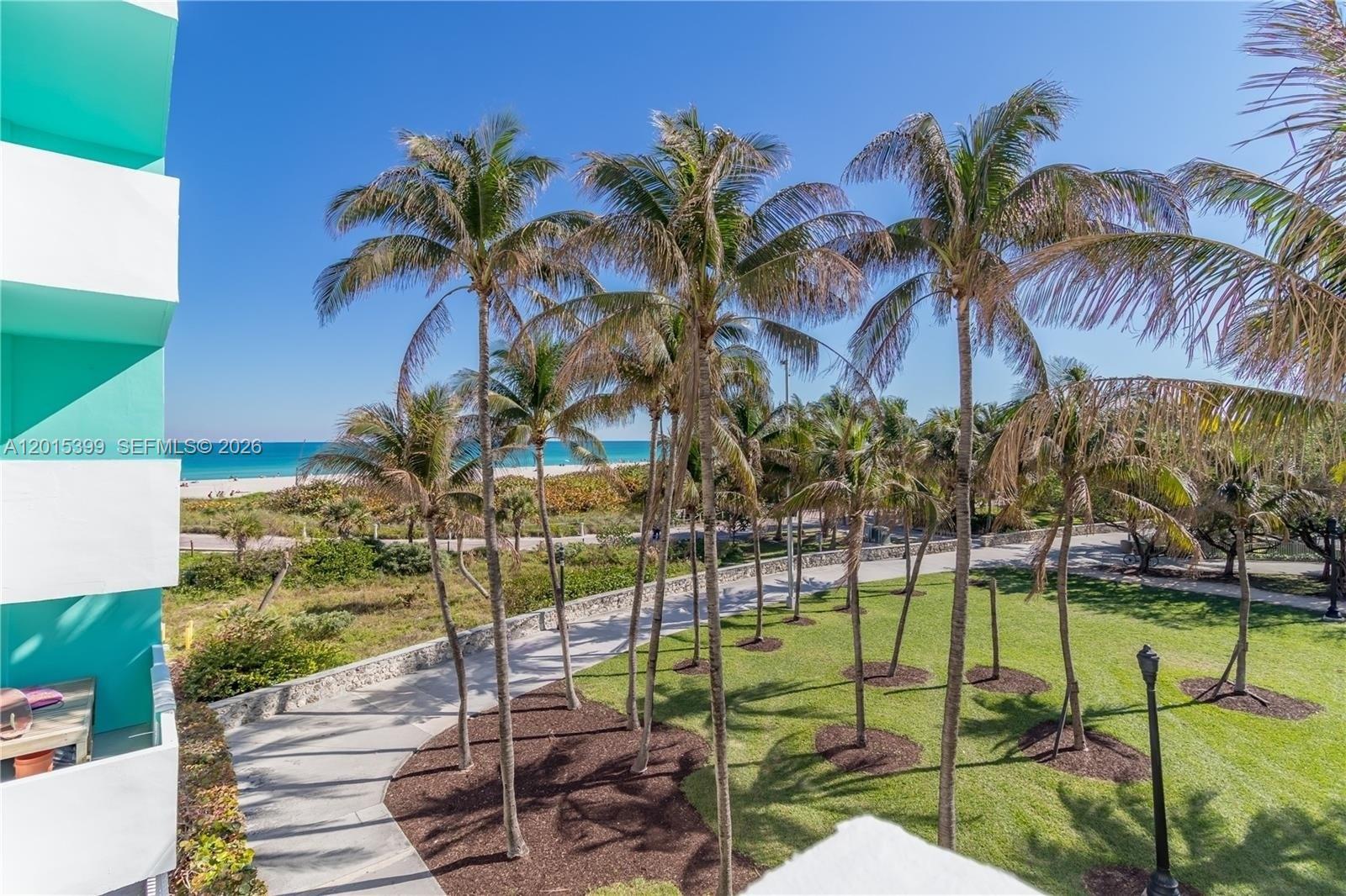 An elevated view shows a grassy park with palm trees leading to a sandy beach — 301 Ocean Dr # 306, Miami Beach FL 33139, MIAMI BEACH, FL