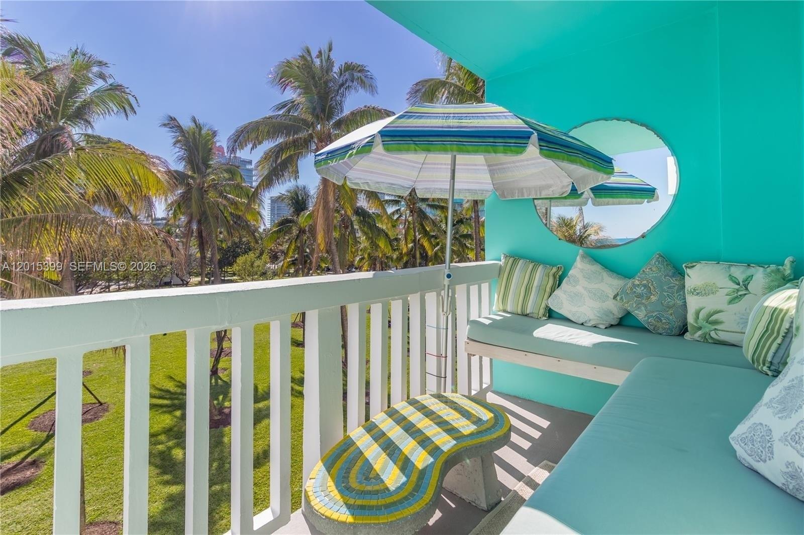 A turquoise balcony features a built-in bench, a mosaic table, and a striped umbrella — 301 Ocean Dr # 306, Miami Beach FL 33139, MIAMI BEACH, FL