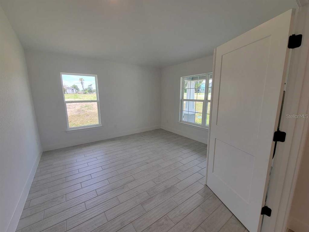An empty room with white walls, light wood-look tile flooring, and two windows — 13060 SW 38TH TERRACE, OCALA, FL