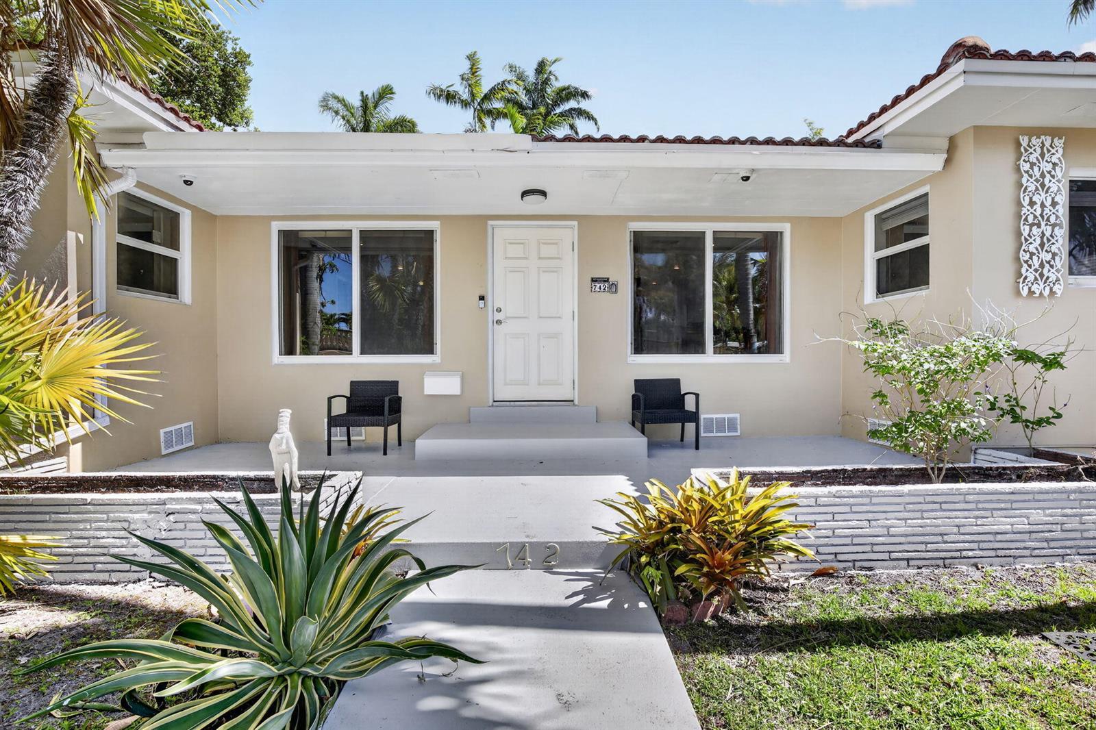 The exterior of a single-story house features a covered porch, two chairs, and landscaping — 742 Hollywood Boulevard, Hollywood FL 33019, HOLLYWOOD, FL