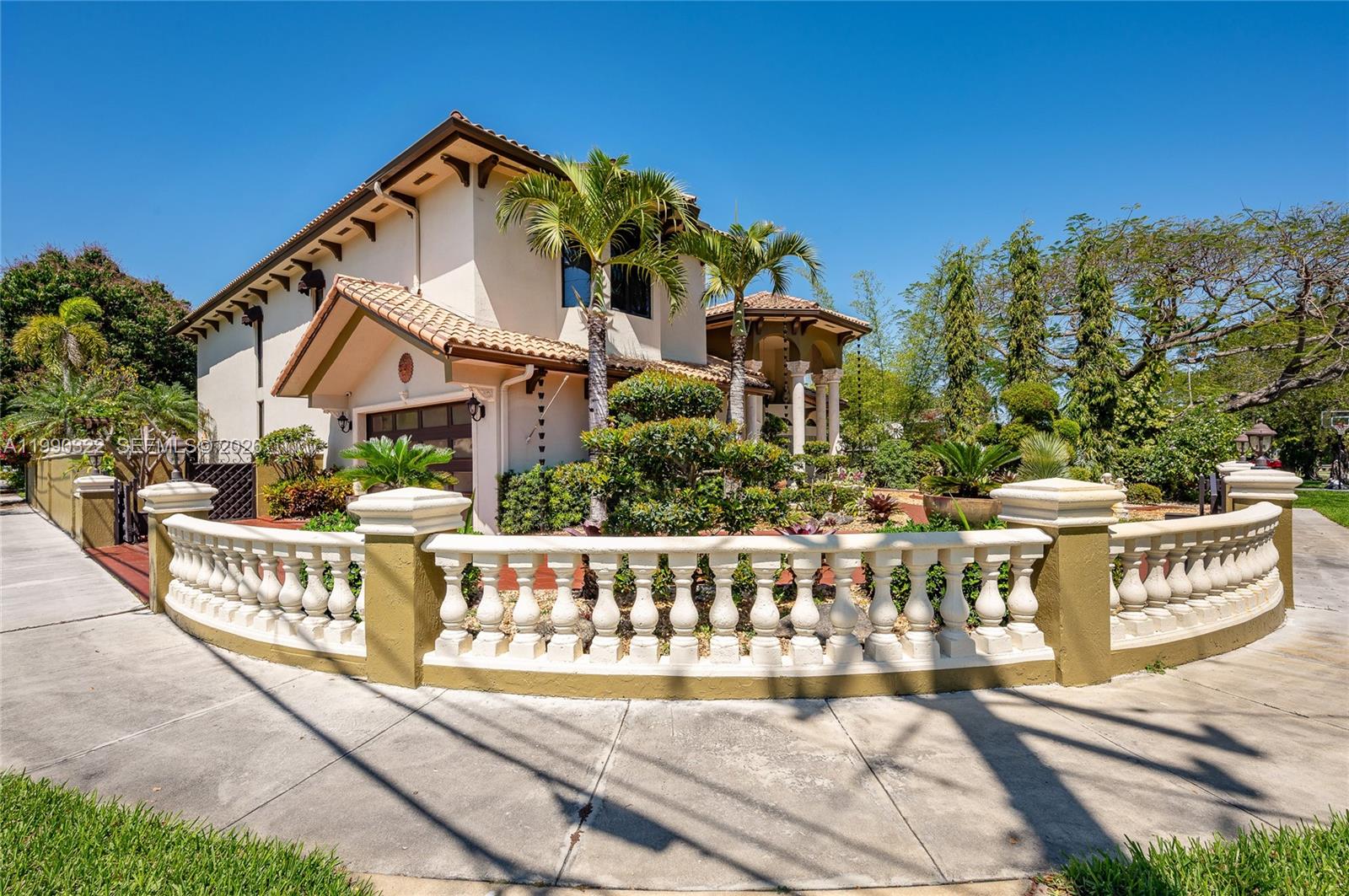 A two-story stucco house with a tiled roof sits behind a curved stone balustrade fence — 588 Miller Dr, Miami Springs FL 33166, MIAMI SPRINGS, FL