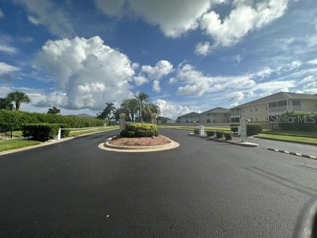 A paved road leads to a landscaped traffic circle in front of residential apartment buildings — 5800 SABAL TRACE DRIVE UNIT 603, NORTH PORT, FL