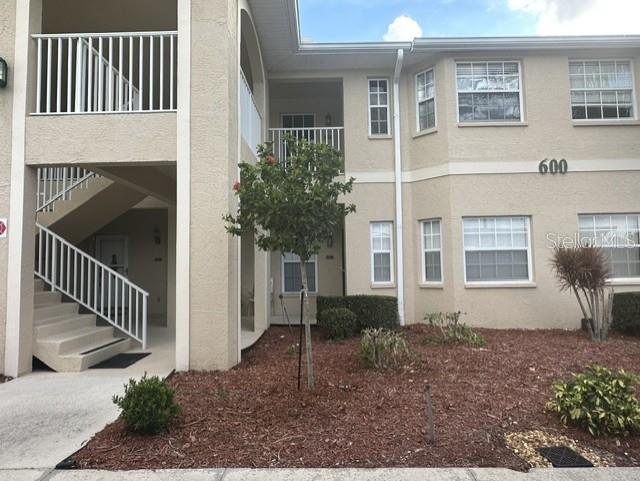A beige two-story apartment building features white railings, exterior stairs, and landscaped mulch beds — 5800 SABAL TRACE DRIVE UNIT 603, NORTH PORT, FL
