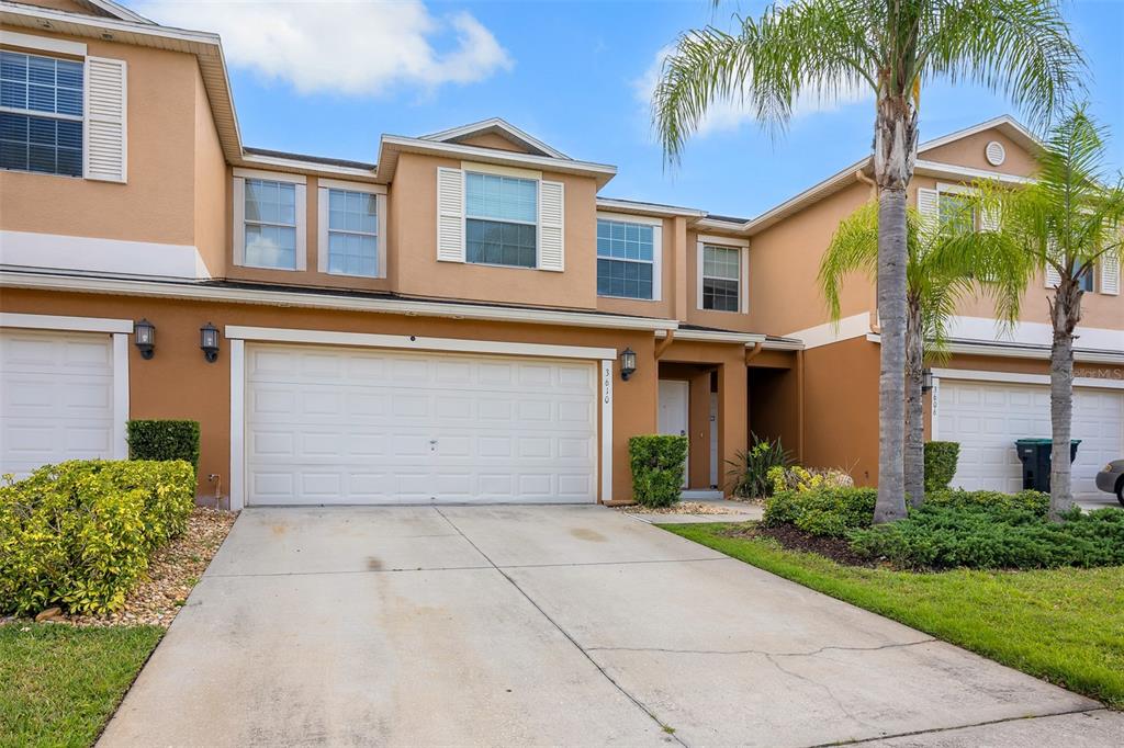 A two-story tan townhouse with a white garage door and a concrete driveway — 3610 RODRICK CIRCLE, ORLANDO, FL