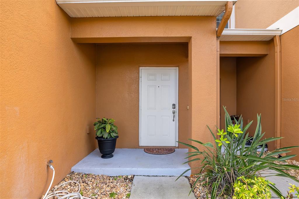 A white front door is centered on a covered porch with orange stucco walls — 3610 RODRICK CIRCLE, ORLANDO, FL