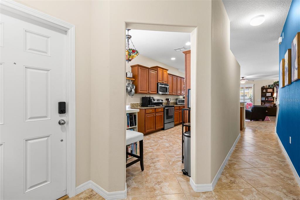 A view from an entryway looking into a kitchen with wood cabinets and tile floors — 9524 TRUMPET VINE LOOP, NEW PORT RICHEY, FL