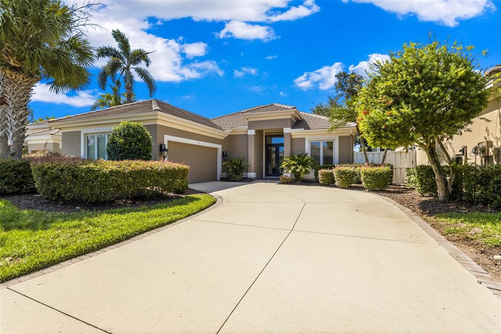 A single-story house with a beige exterior, a concrete driveway, and a manicured front lawn — 8762 52ND AVENUE E, BRADENTON, FL