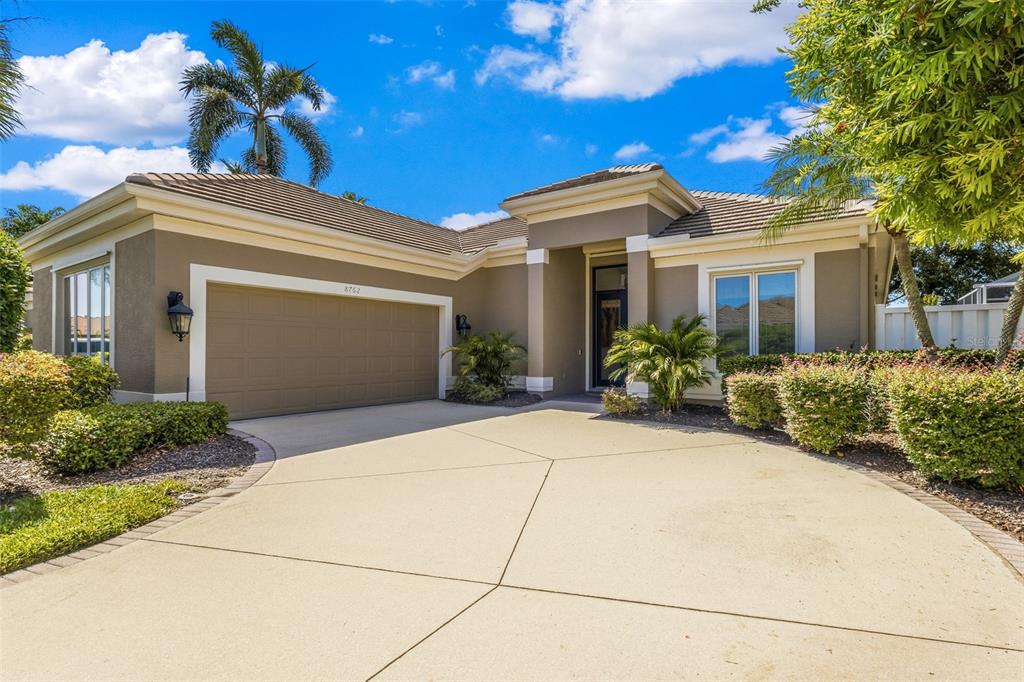 A single-story house with a tan stucco exterior, a two-car garage, and a concrete driveway — 8762 52ND AVENUE E, BRADENTON, FL