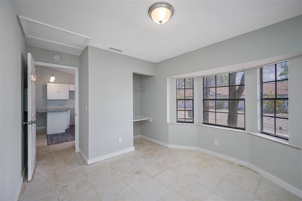A room with light gray walls, tile flooring, a built-in desk, and a bay window — 501 ST. MICHAELS WAY UNIT 500, TARPON SPRINGS, FL