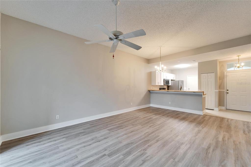 A living room with light wood-look flooring, a ceiling fan, and an open kitchen — 1032 RADISON AVENUE UNIT 2, SUN CITY CENTER, FL