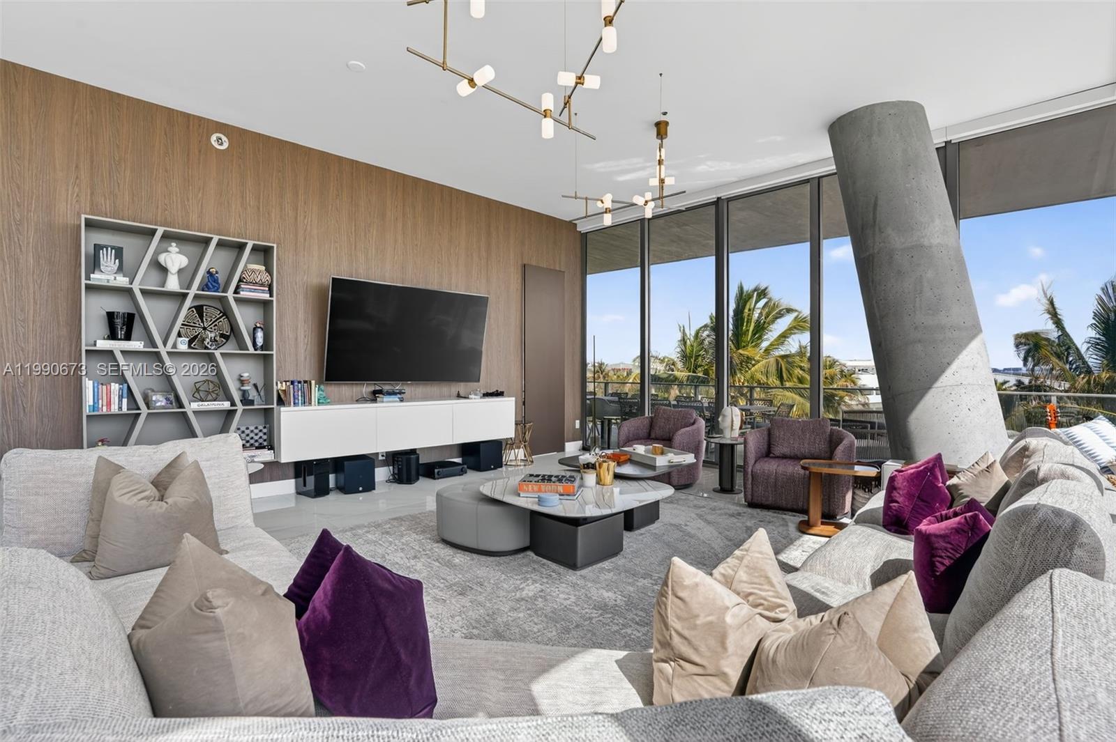 A modern living room features a large sectional sofa, wood-paneled wall, and floor-to-ceiling windows — 2675 S Bayshore Dr # 402S, Miami FL 33133, MIAMI, FL