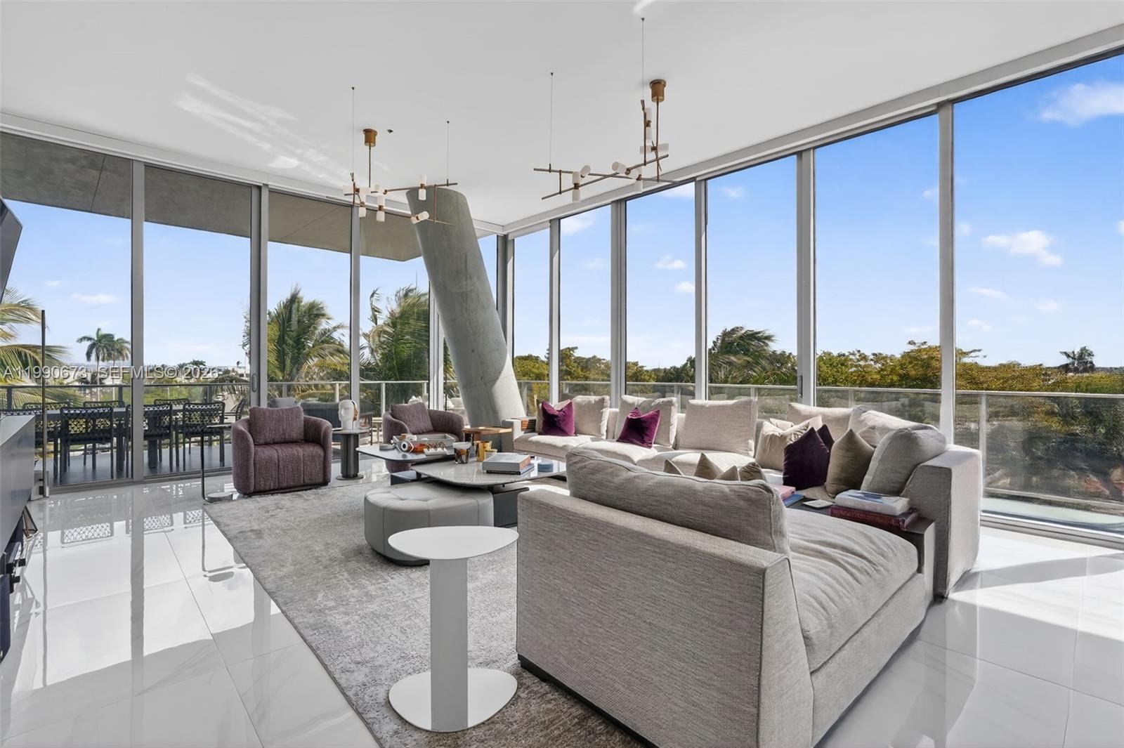 A bright living room features floor-to-ceiling windows, a large sectional sofa, and a concrete column — 2675 S Bayshore Dr # 402S, Miami FL 33133, MIAMI, FL