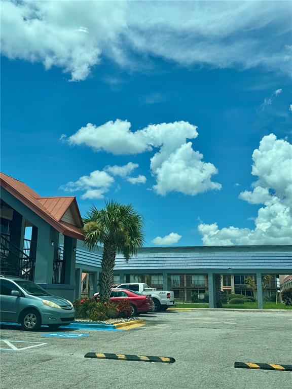 A parking lot sits in front of a multi-story building with a palm tree — 43420 HIGHWAY 27 UNIT 421, DAVENPORT, FL