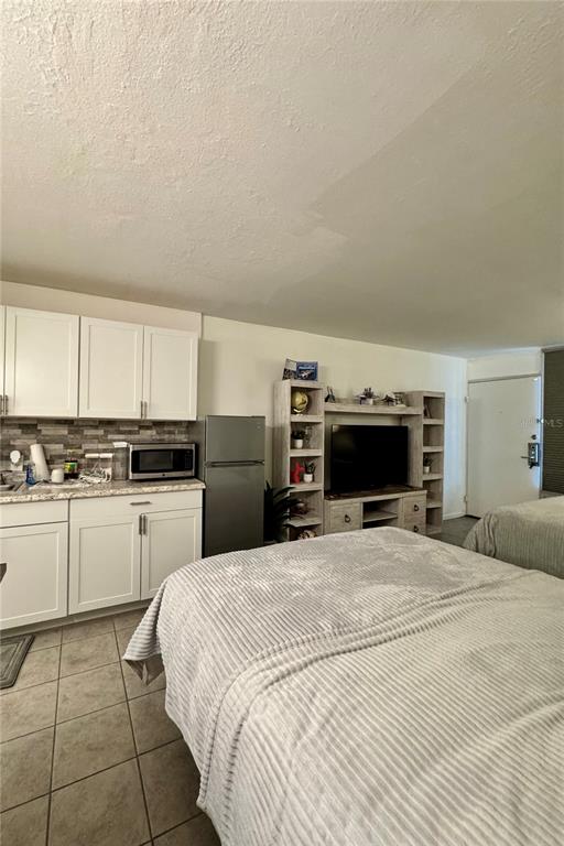 A studio apartment features a kitchenette with white cabinets, a refrigerator, and a bed — 43420 HIGHWAY 27 UNIT 421, DAVENPORT, FL