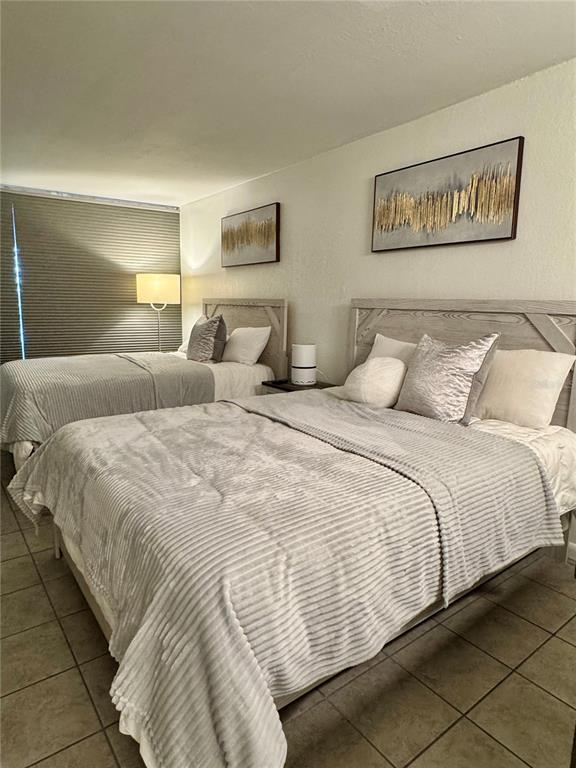 A bedroom features two beds with gray textured bedding and matching headboards on a tiled floor — 43420 HIGHWAY 27 UNIT 421, DAVENPORT, FL