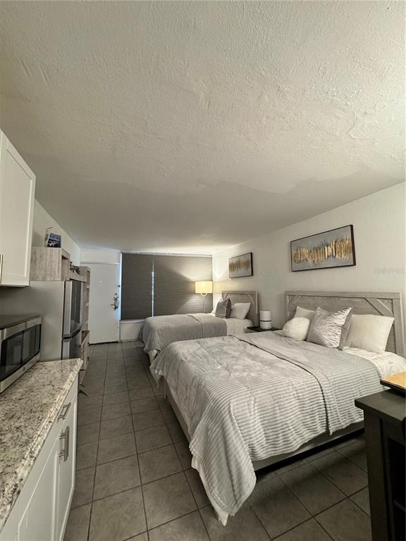 A studio apartment features two beds, a small kitchenette, and tile flooring — 43420 HIGHWAY 27 UNIT 421, DAVENPORT, FL