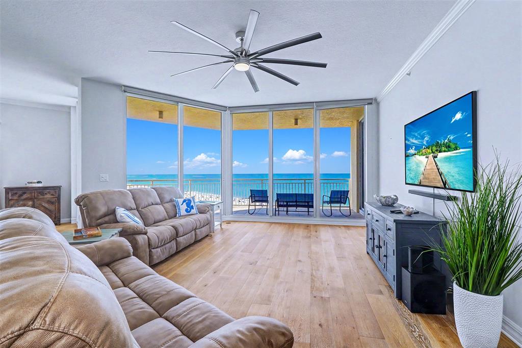 A living room features light wood floors, a large ceiling fan, and ocean-view windows — 15208 GULF BOULEVARD UNIT 601, MADEIRA BEACH, FL