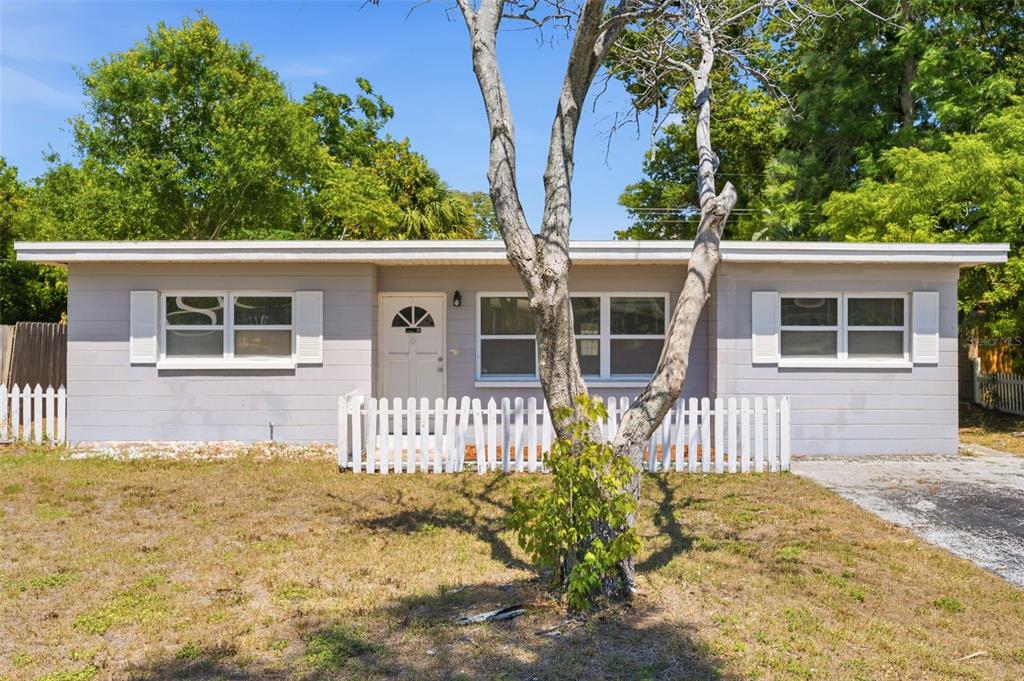 A single-story house with light gray siding, white shutters, and a small white picket fence — 8871 93RD STREET, SEMINOLE, FL