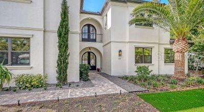 The exterior of a two-story stucco home features a paved walkway, arched entryway, and palm tree — 1850 WEBBER STREET, SARASOTA, FL