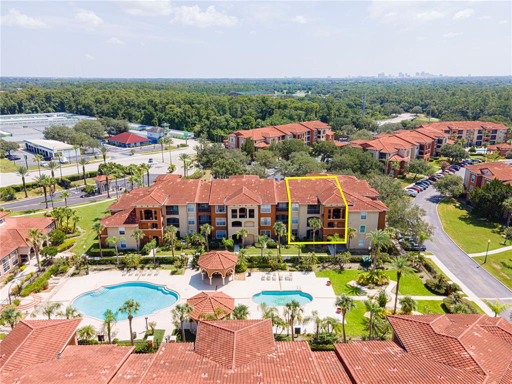 An aerial view shows a multi-story apartment building with a pool and surrounding landscaping — 5500 METROWEST BOULEVARD UNIT 14-203, ORLANDO, FL