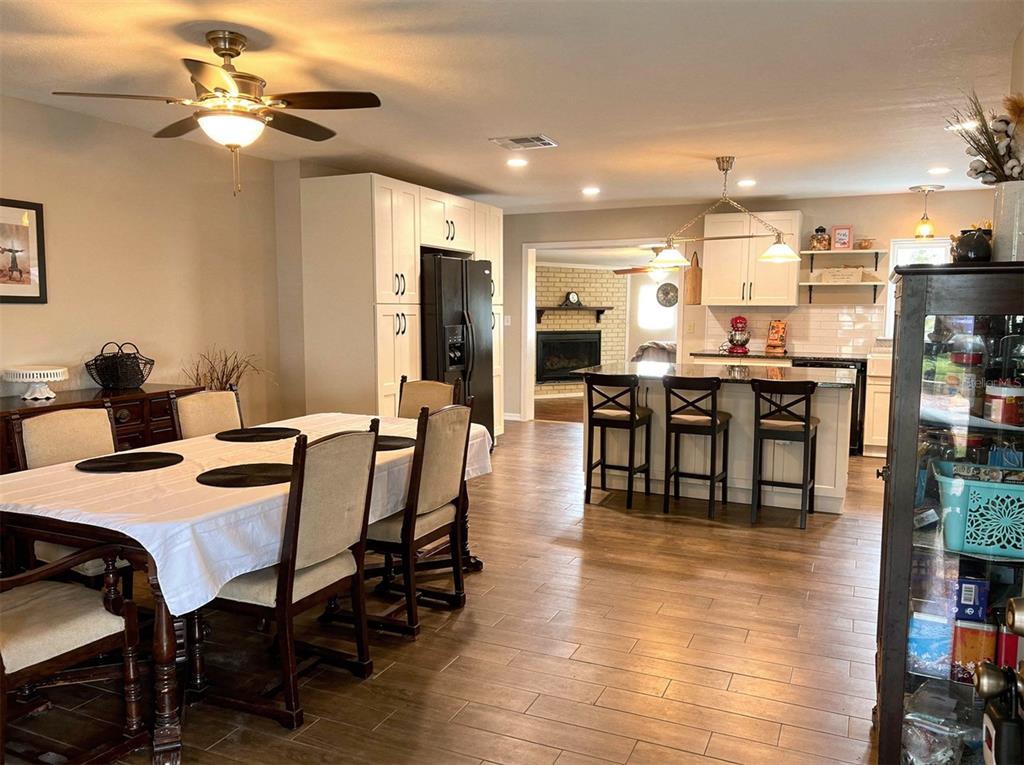 An open-concept dining room and kitchen with wood-look tile flooring and a central island — 2009 NE 51ST PLACE, OCALA, FL