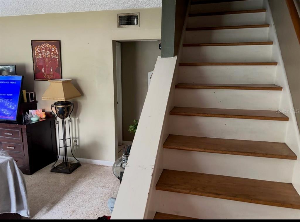 A staircase with wooden treads and white risers stands next to a living area — 12728 83RD AVENUE, SEMINOLE, FL