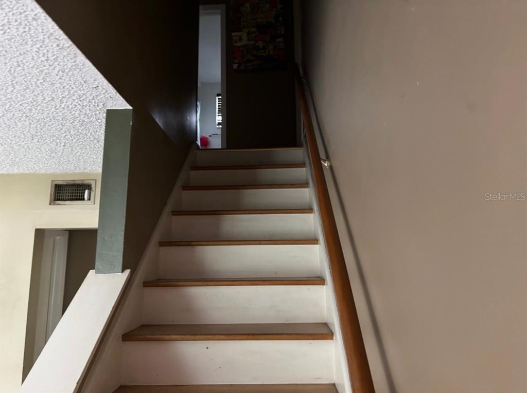 A staircase with white risers and wood treads leads to a landing with a doorway — 12728 83RD AVENUE, SEMINOLE, FL