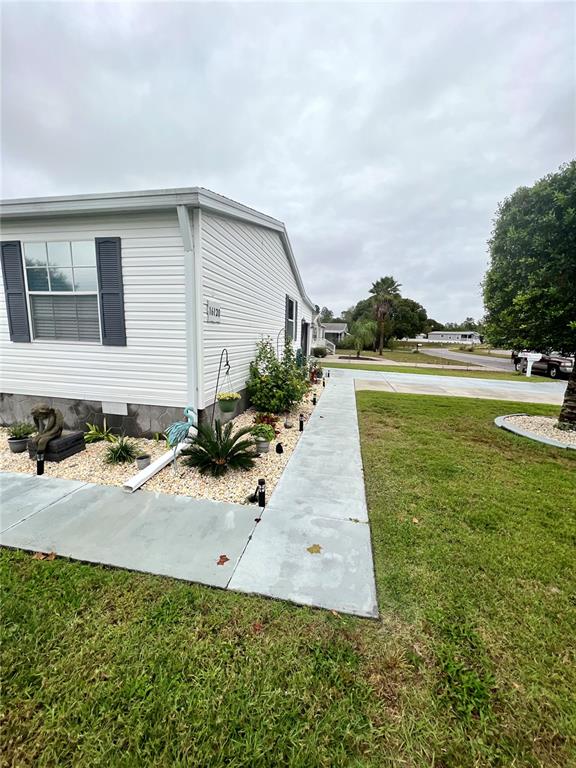 The exterior of a white mobile home features light-colored siding, dark shutters, and a concrete walkway — 16120 BROOKRIDGE BOULEVARD, BROOKSVILLE, FL