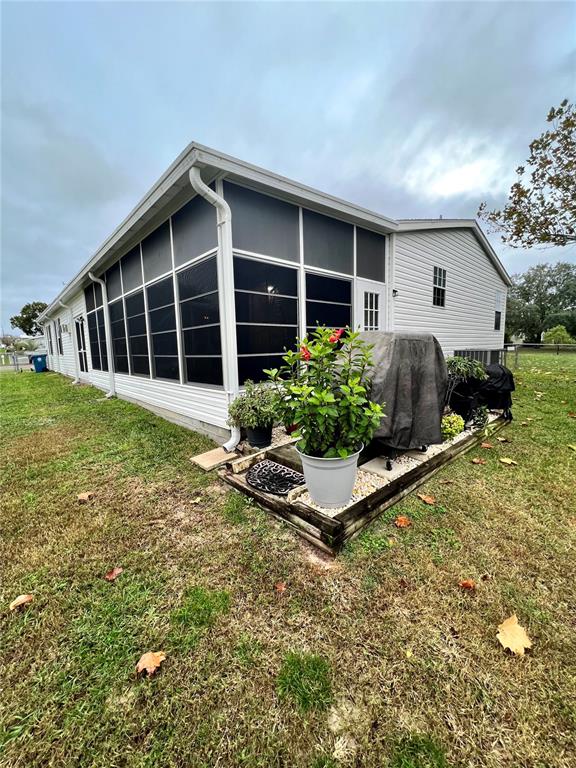 The exterior of a house features a screened-in porch and a small landscaped garden bed — 16120 BROOKRIDGE BOULEVARD, BROOKSVILLE, FL