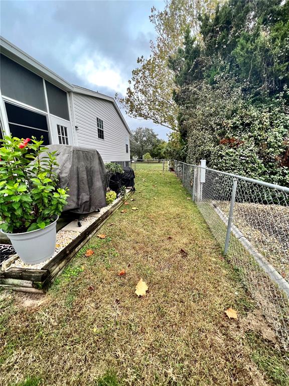 A side yard features a covered grill, a potted plant, and a chain-link fence — 16120 BROOKRIDGE BOULEVARD, BROOKSVILLE, FL