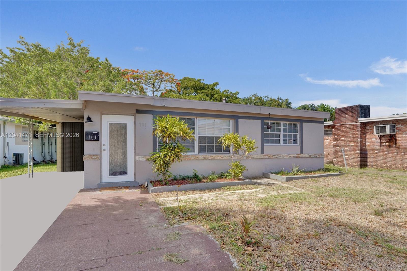 A single-story house with a flat roof, a carport, and a brick chimney exterior — 701 SW 7th St, Pompano Beach FL 33060, POMPANO BEACH, FL