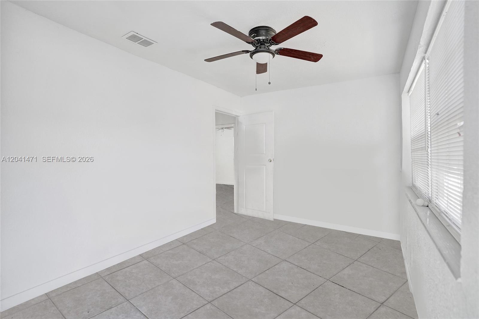 A room with white walls, gray tile flooring, a ceiling fan, and a window — 701 SW 7th St, Pompano Beach FL 33060, POMPANO BEACH, FL