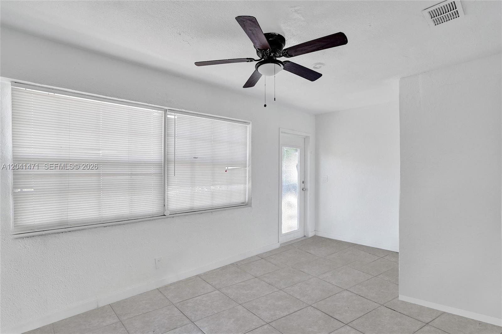 A sunroom features white walls, light-colored tile flooring, a ceiling fan, and large windows — 701 SW 7th St, Pompano Beach FL 33060, POMPANO BEACH, FL