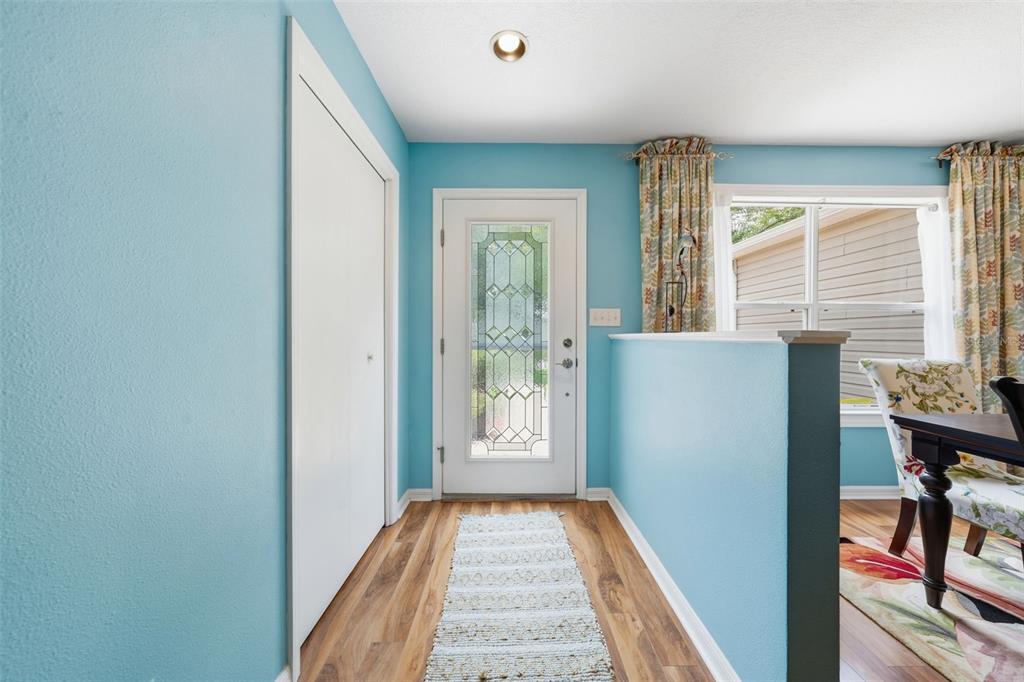 An entryway with light blue walls, wood-look flooring, a white front door, and a closet — 1602 MALACARA LANE, THE VILLAGES, FL