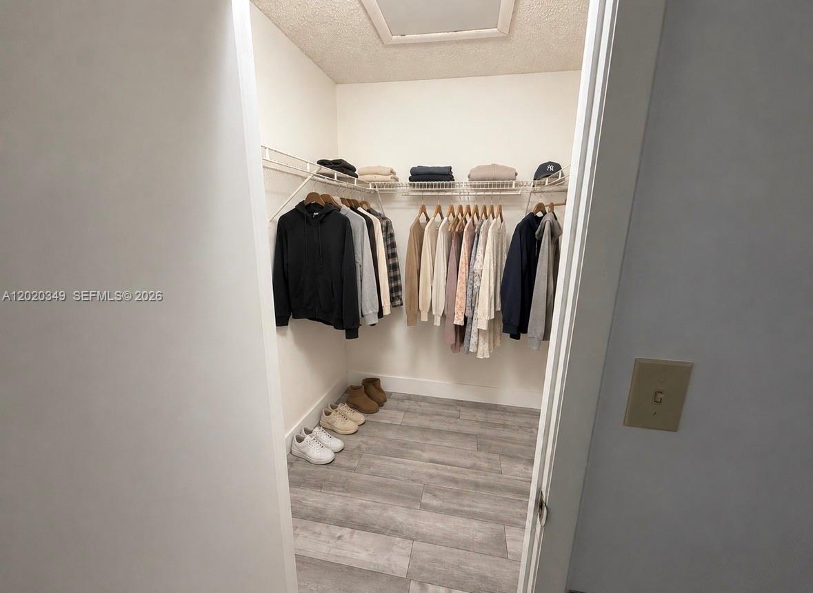 A walk-in closet features white wire shelving, hanging clothes, and light wood-look flooring — 10440 SW 156th Ct # 726, Miami FL 33196, MIAMI, FL