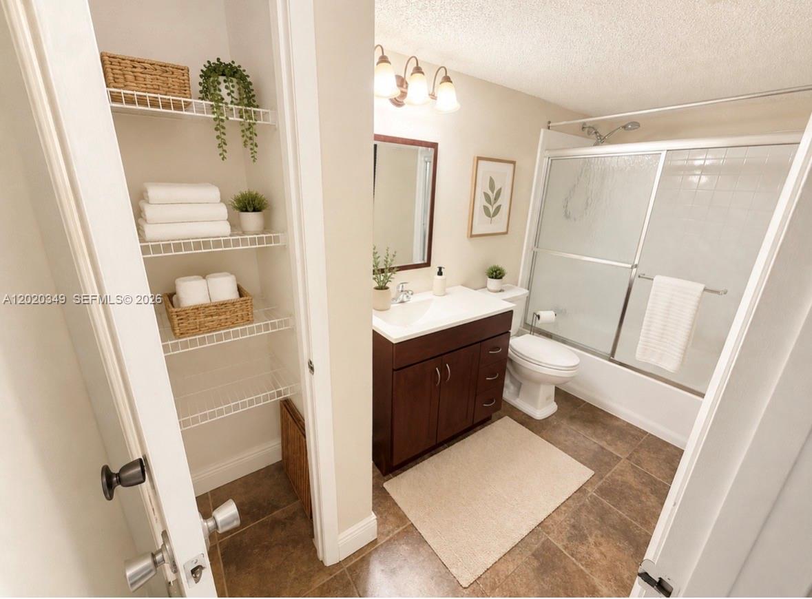 A bathroom features a dark wood vanity, a shower-tub combo, and open wire shelving — 10440 SW 156th Ct # 726, Miami FL 33196, MIAMI, FL